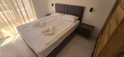 a bed with white sheets and white towels on it at Apartmani Banović 3 - Ulcinj, Velika plaža in Ulcinj
