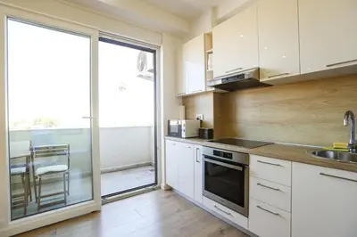 a kitchen with white cabinets and a large window at Apartmani Stefan in Bar