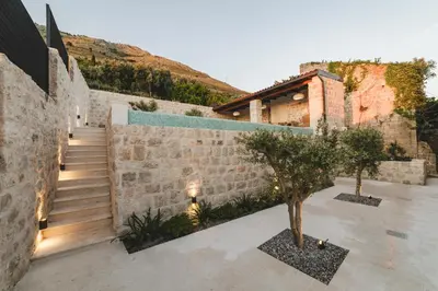 a house with a stone wall and stairs with trees at Villa Boscovich in Katun