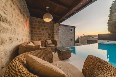 a patio with wicker chairs and a table and a pool at Villa Boscovich in Katun