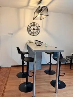 a table and chairs in a room with a clock at Alex Apartment Petrovac in Petrovac na Moru