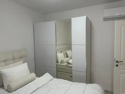 a white bedroom with a bed and a mirror at Villa Zaljevo in Bar