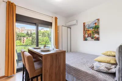 a bedroom with a bed and a desk and a window at Summer Nest Studio in Becici in Becici