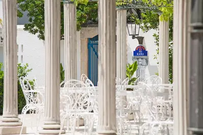 a group of white tables and chairs in front of a building at Hotel Slovenska Plaza in Budva
