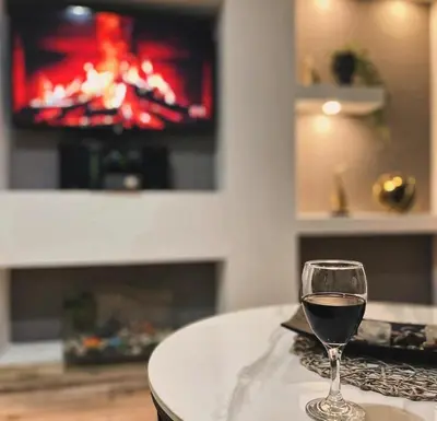 a glass of wine sitting on a table with a television at Uživajte u mirnom i elegantnom smještaju in Podgorica