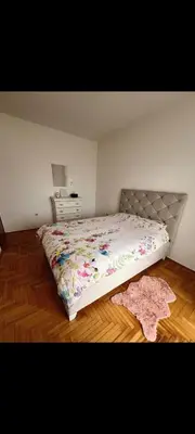 a bedroom with a bed with a floral comforter at Uživajte u mirnom i elegantnom smještaju in Podgorica