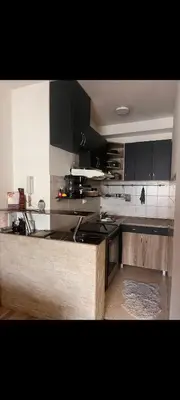 a kitchen with black cabinets and a counter top at Uživajte u mirnom i elegantnom smještaju in Podgorica