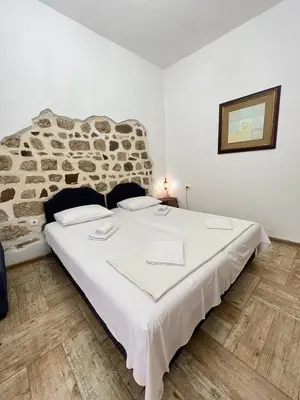 a large white bed in a room with a stone wall at Royal House in Kotor