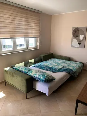 a bed in a room with a couch and a window at Modern 1BR - Old Town and sea in Budva