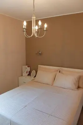 a bedroom with a white bed with a chandelier at Modern 1BR - Old Town and sea in Budva