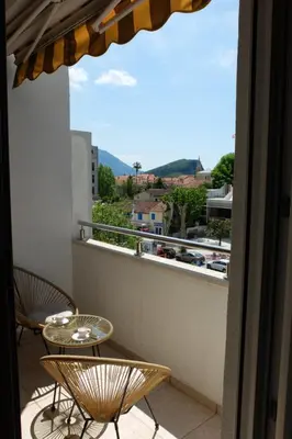 a balcony with two tables and a view of a city at Modern 1BR - Old Town and sea in Budva