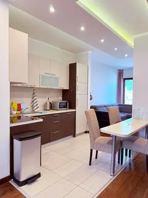 a kitchen and living room with a table and chairs at Apartment in the Lusitanos in Budva