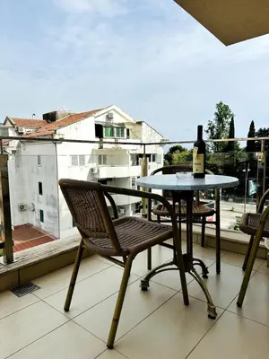a table and chair with a bottle of wine on a balcony at Apartment in the Lusitanos in Budva