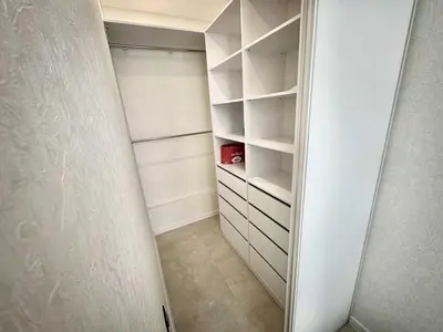 a walk in closet with white shelves and a door at Apartman Velsma in Budva