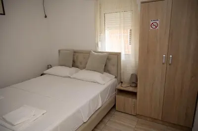 a small bedroom with a bed and a wooden cabinet at apartmani DENI in Donji Štoj