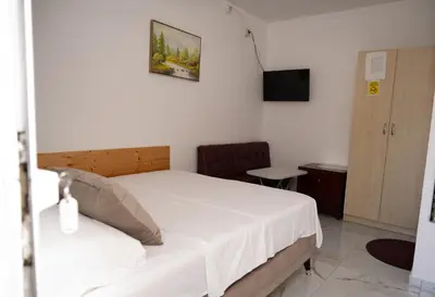 a bedroom with a white bed and a television at apartmani DENI in Donji Štoj