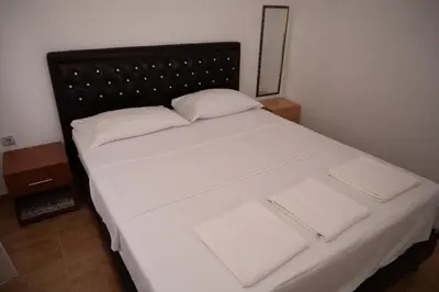 a bed with white sheets and pillows in a room at apartmani DENI in Donji Štoj