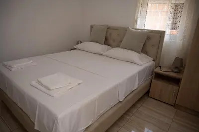 a bed with white sheets and white towels on it at apartmani DENI in Donji Štoj