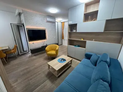a living room with a blue couch and a tv at Apartment Oaza in Budva