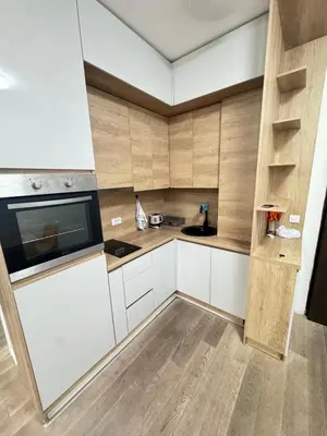 a small kitchen with white cabinets and wooden walls at Apartment Oaza in Budva
