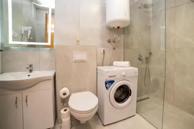 a bathroom with a washing machine and a sink at LA PERLA apartments 14 in Ulcinj