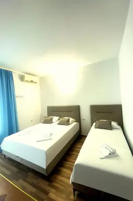 two beds in a room with blue curtains at Apartments Hija in Donji Štoj