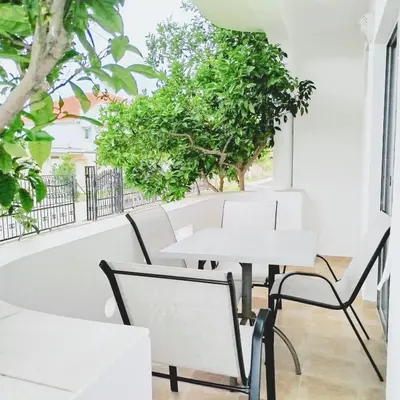 a white table and chairs in a room with trees at Apartments Hija in Donji Štoj