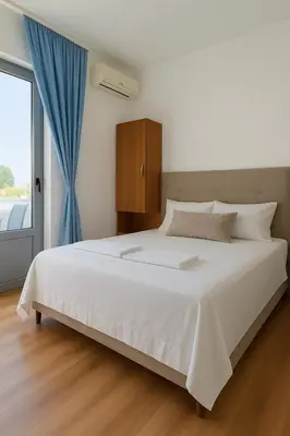a bedroom with a large white bed with a blue curtain at Apartments Hija in Donji Štoj