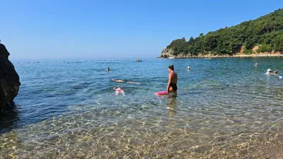 a man standing in the water at a beach at Доброморе Будва in Budva