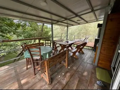 a screened in porch with a table and chairs at Kucica obala in Železnička Stanica Zeta