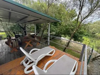 a deck with white chairs and a picnic table at Kucica obala in Železnička Stanica Zeta