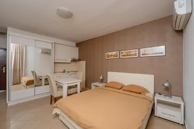 a bedroom with a bed and a table and a kitchen at Vanila Apartmani in Sutomore