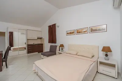 a bedroom with a bed and a desk and a kitchen at Vanila Apartmani in Sutomore
