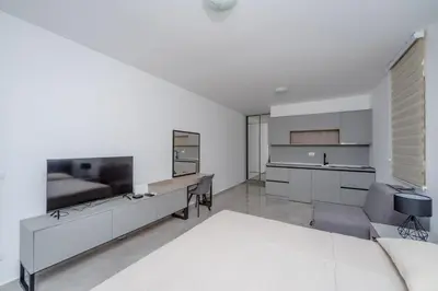 a white room with a bed and a kitchen at Vanila Apartmani in Sutomore