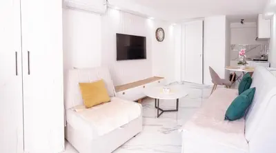 a white living room with a couch and a table at Mia Studio Apartment in Budva