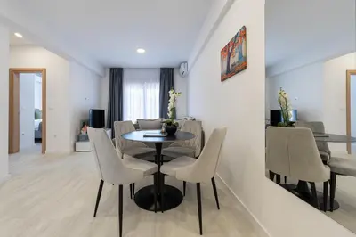 a dining room and living room with a table and chairs at Millennium Apartments Budva in Budva