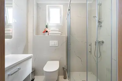 a bathroom with a toilet and a glass shower at Millennium Apartments Budva in Budva