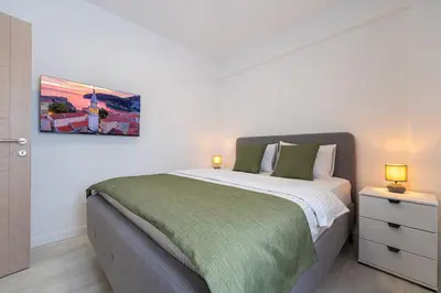 a bedroom with a large bed and two lamps at Millennium Apartments Budva in Budva