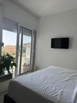 a white bedroom with a bed and a flat screen tv at Best Apartments in Ulcinj