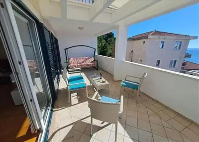 a balcony with chairs and a couch and a table at Three bedrooms family apartment with sea view Sveti Stefan in Sveti Stefan