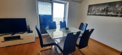 a dining room with a table and chairs and a television at Three bedrooms family apartment with sea view Sveti Stefan in Sveti Stefan