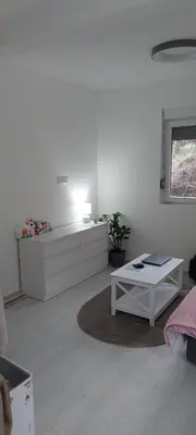 a white room with a bed and a table at White apartment in Sutomore