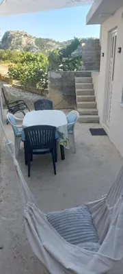 a patio with a table and chairs and a hammock at White apartment in Sutomore