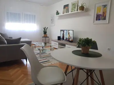 a living room with a white table and a couch at Spacious and comfortable apartment in Podgorica