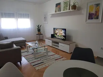 a living room with a tv and a couch and a table at Spacious and comfortable apartment in Podgorica