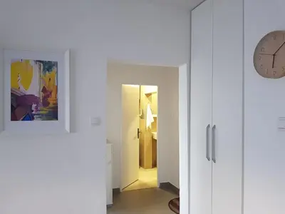 a hallway with a clock on the wall and a white door at Spacious and comfortable apartment in Podgorica