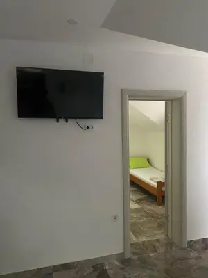 a flat screen tv on a wall next to a bedroom at Bayview Apartments in Drobnići