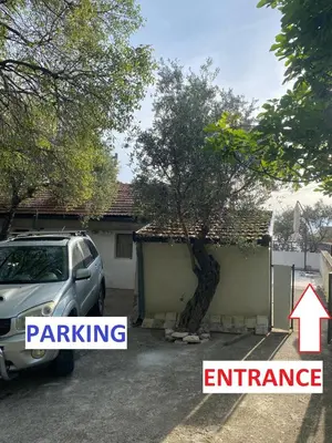 a car parked in front of a house with a tree at Bayview Apartments in Drobnići