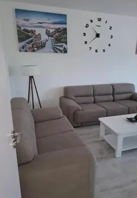 a living room with a couch and a clock on the wall at Milovic Apartman in Kotor
