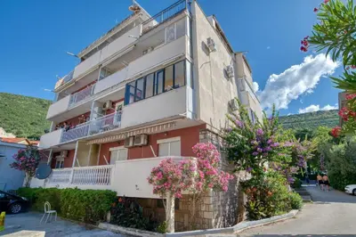 a building with pink flowers in front of it at Apartman Centar in Petrovac na Moru